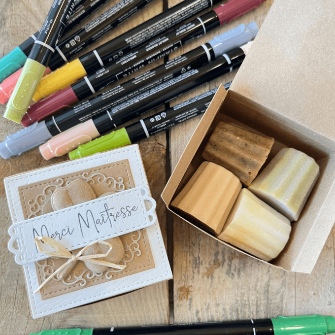 Boîte cadeau contenant quatre savons artisanaux en forme de cannelés, avec étiquette "Merci maîtress