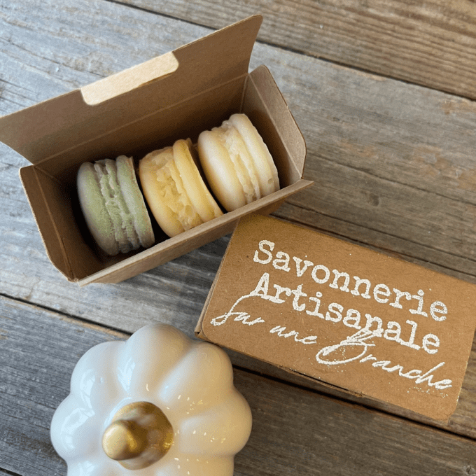 Coffret kraft contenant trois savons artisanaux en forme de macarons clairs, fabriqués à la main par