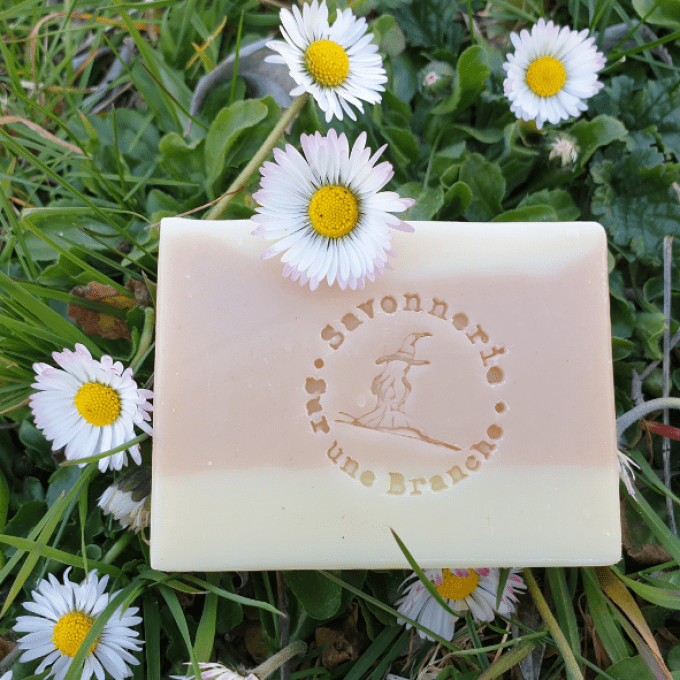 savon solide artisanal argile rose posé dans une prairie