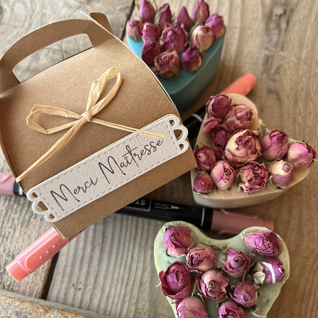 Savon en forme de cœur décoré de boutons de rose séchés, présenté dans une boîte kraft avec étiquette "Merci maîtresse".